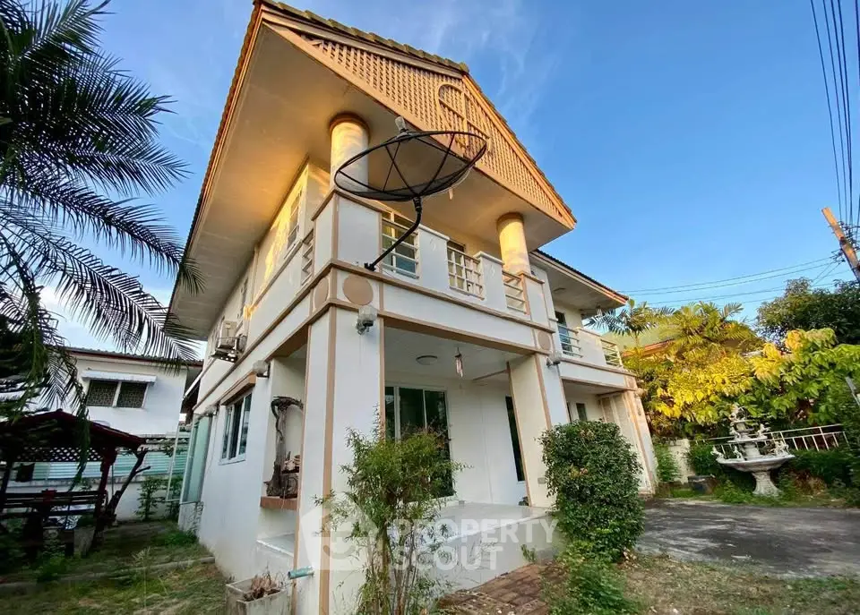 Charming two-story house with lush garden and satellite dish, perfect for family living.