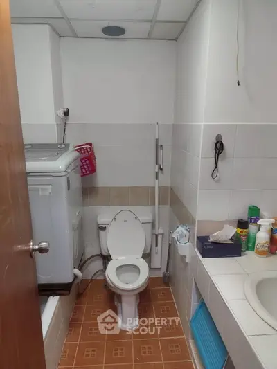 Compact bathroom with washing machine and essential amenities in a cozy setting.