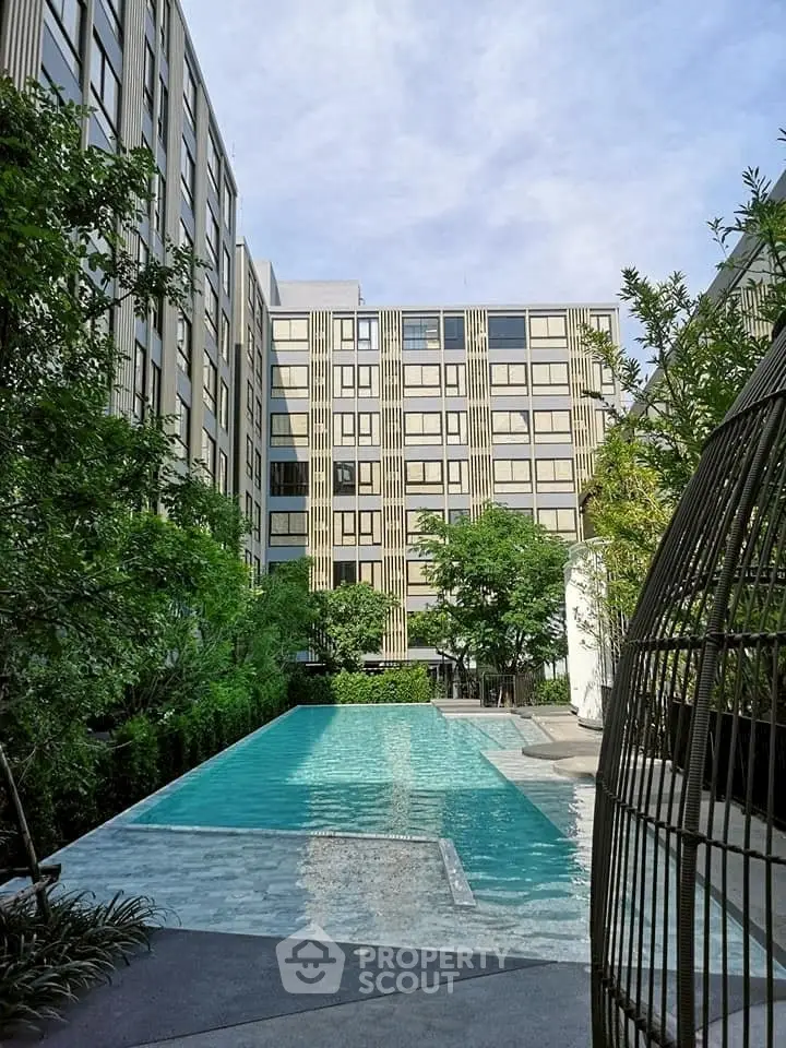 Luxurious apartment complex with stunning outdoor pool and lush greenery.