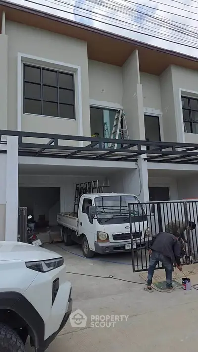 Modern townhouse exterior with large windows and garage under construction.