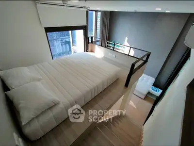 Modern loft bedroom with mezzanine and large windows offering city views.