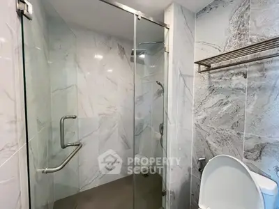 Modern bathroom with glass shower and marble tiles, featuring sleek fixtures and elegant design.