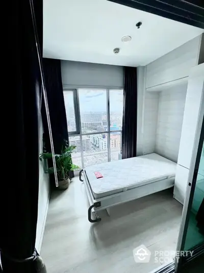 Modern bedroom with city view, featuring large window and minimalist decor.