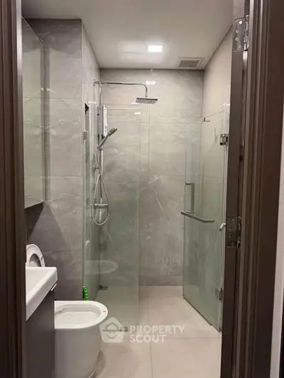 Modern bathroom with sleek glass shower and contemporary fixtures in a stylish apartment.