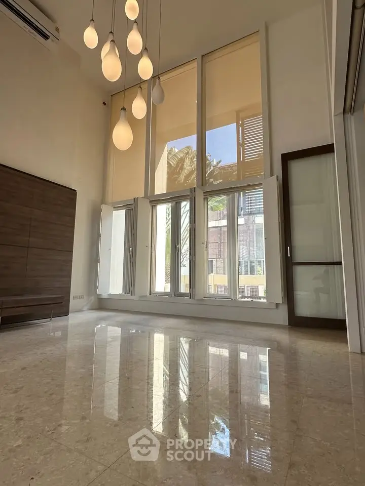 Spacious living room with high ceilings and elegant lighting in modern apartment.