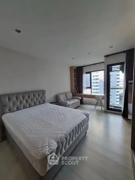 Modern bedroom with city view, featuring a plush bed and stylish decor.