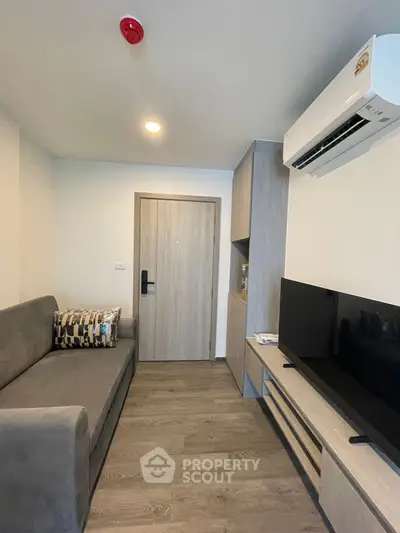 Modern living room with sleek furniture and wall-mounted TV in a cozy apartment.