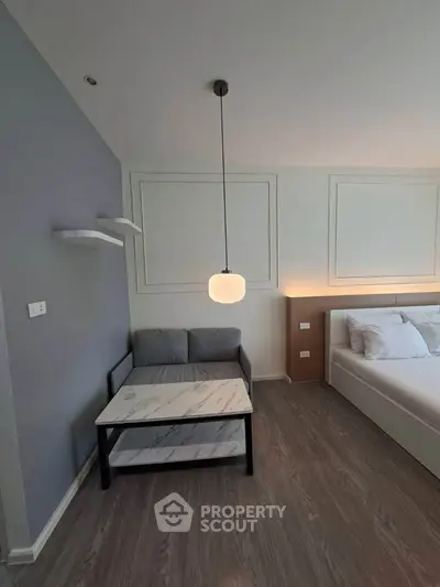 Modern bedroom with stylish decor and cozy seating area, featuring elegant lighting and contemporary design.