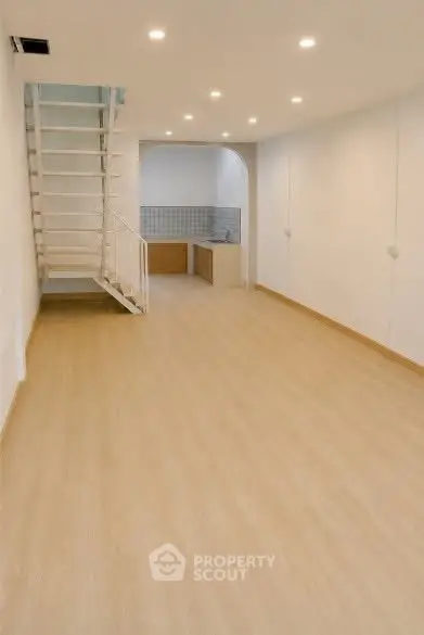 Spacious modern interior with wooden flooring and staircase, ideal for open-plan living.