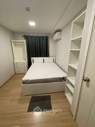 Cozy bedroom with modern white furniture and wooden flooring, perfect for a restful retreat.