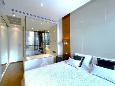 Luxurious bedroom with modern design and glass-walled ensuite bathroom featuring a bathtub.