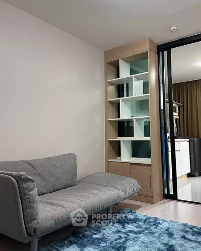 Modern living room with stylish gray sofa and built-in shelving unit, featuring a cozy blue rug.