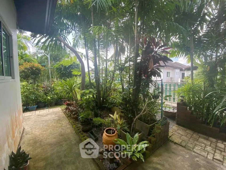 Charming garden view with lush greenery and paved walkway in residential area.