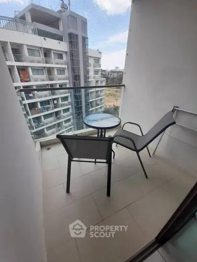 Charming balcony with seating and city view in modern apartment complex.