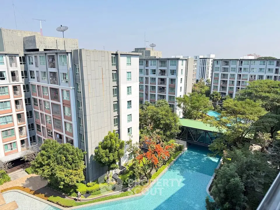 Stunning aerial view of modern apartment complex with lush greenery and inviting swimming pool.