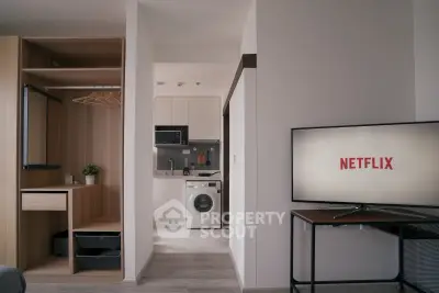 Modern apartment interior with open closet, washing machine, and TV displaying Netflix.
