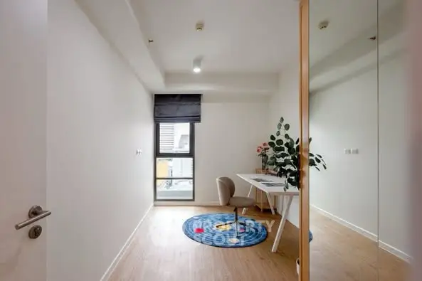 Modern study room with sleek desk and chair, large window, and vibrant round rug.