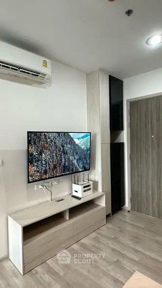 Modern living room with sleek TV setup and stylish wooden flooring.