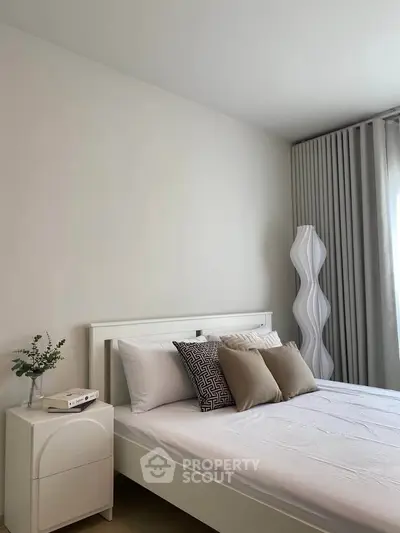 Modern bedroom with stylish decor and natural light, featuring a comfortable bed and elegant curtains.