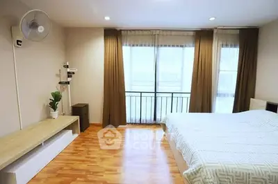 Spacious bedroom with wooden flooring and large windows for natural light.