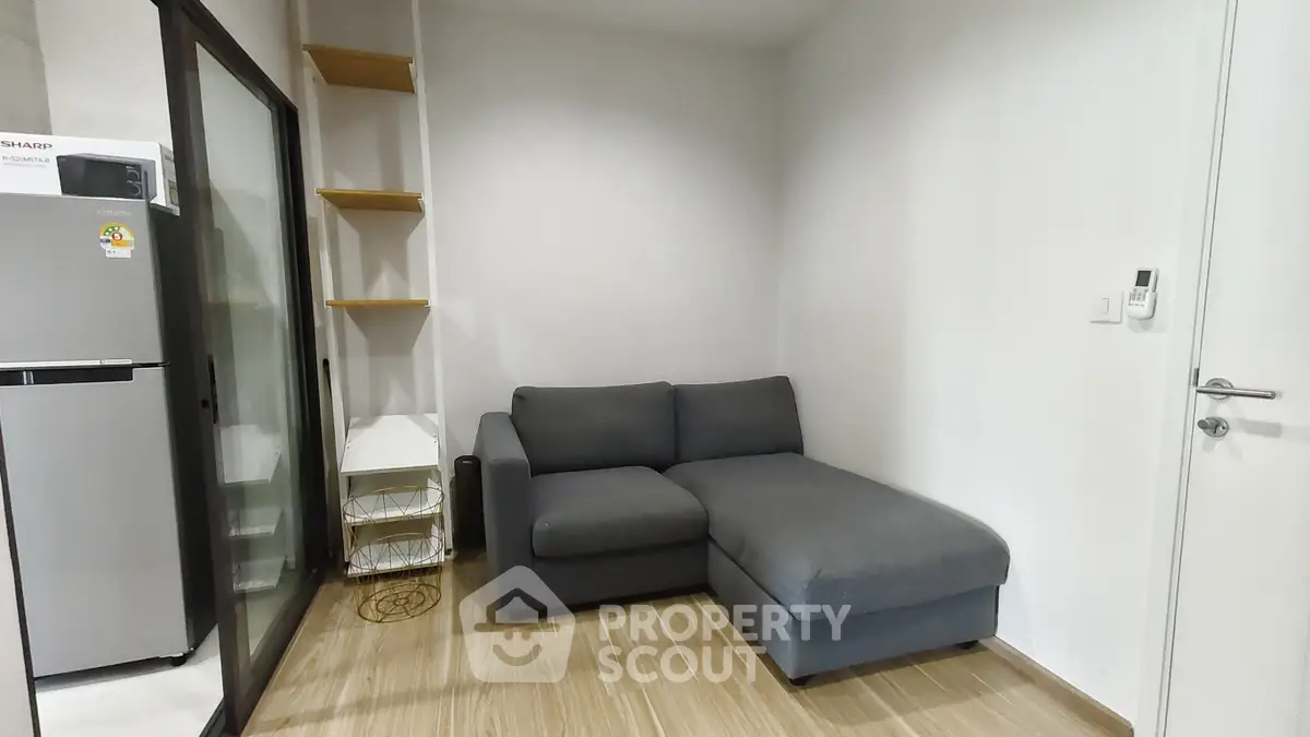 Modern living room with sleek gray sofa and wooden flooring, featuring a minimalist design and ample natural light.
