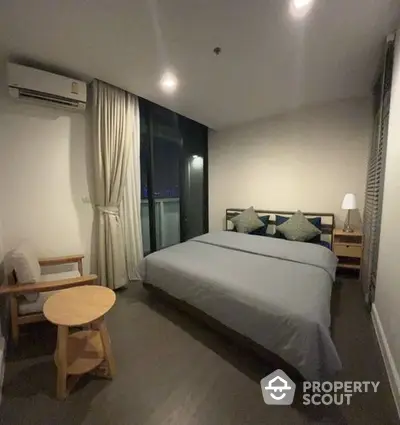 Cozy and well-lit bedroom with a large comfortable bed, wooden flooring, and access to a private balcony offering a serene retreat in a modern apartment.