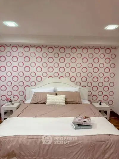 Charming bedroom with stylish circular wallpaper and cozy bedding, perfect for relaxation.