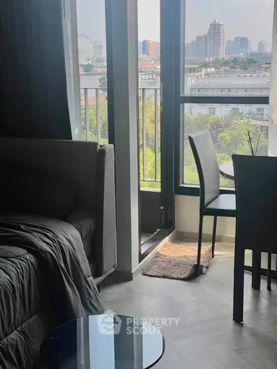 Modern living room with city view and balcony access, featuring sleek furniture and abundant natural light.