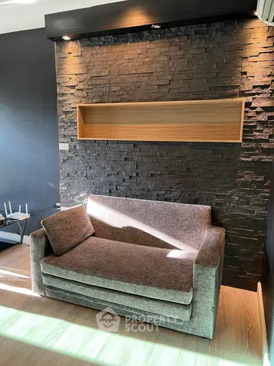 Modern living room with stylish stone accent wall and cozy sofa, perfect for relaxation.