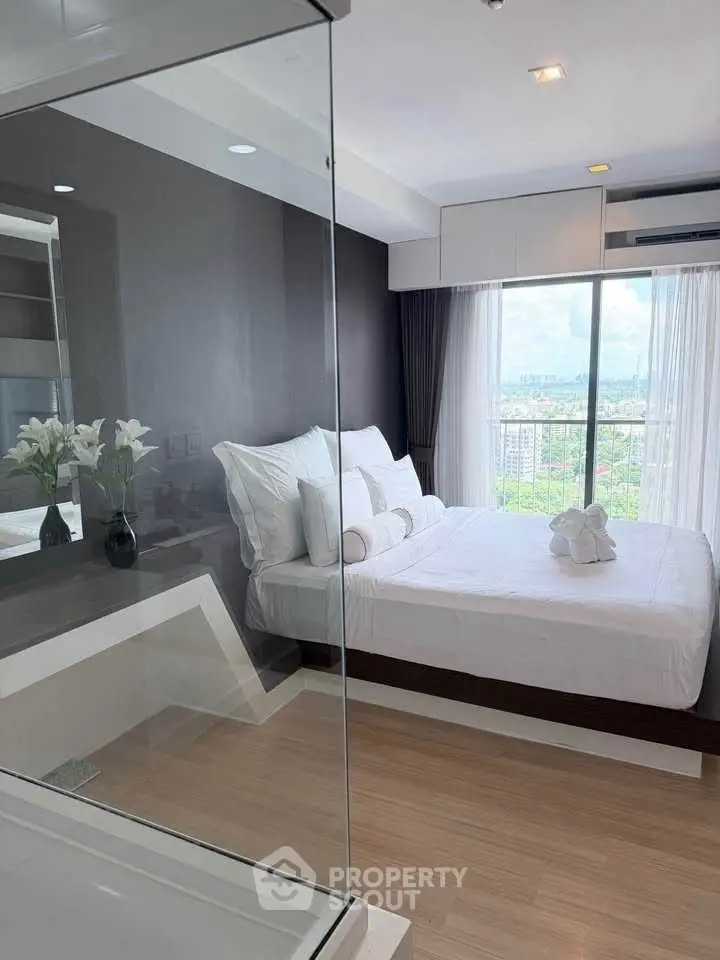 Modern bedroom with glass wall and city view, featuring elegant decor and natural light.