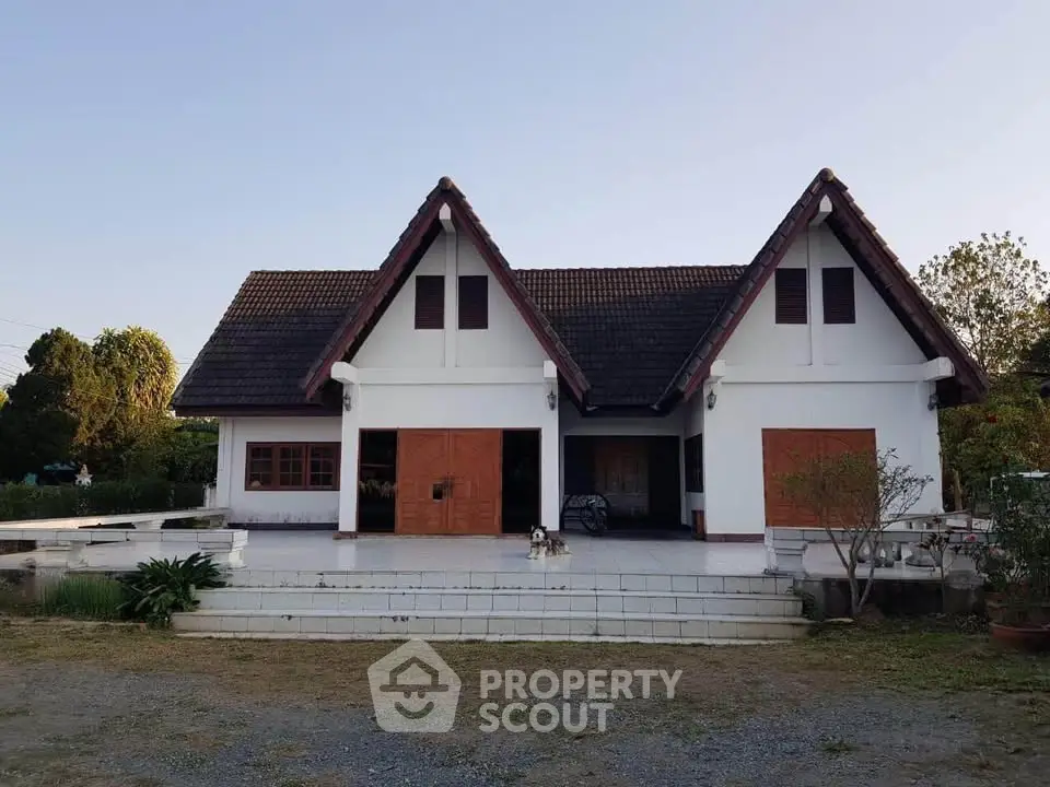 Charming traditional-style house with a spacious front porch and lush greenery, perfect for serene living.