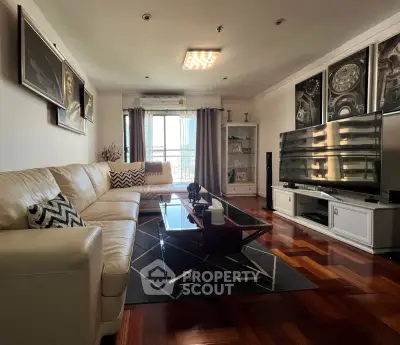 Spacious living room with modern decor and large TV, featuring elegant wooden flooring and stylish artwork.