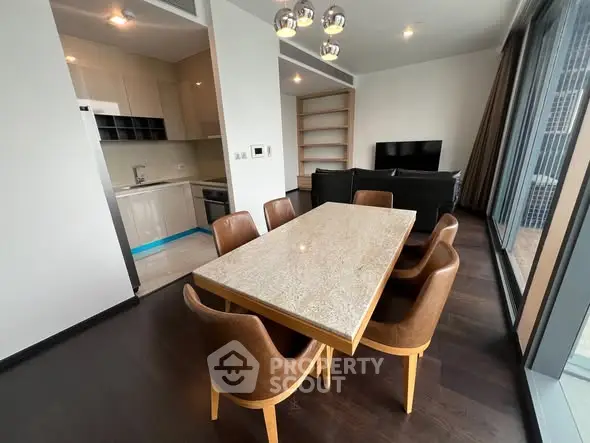 Modern dining area with sleek kitchen and cozy living room in open layout apartment.