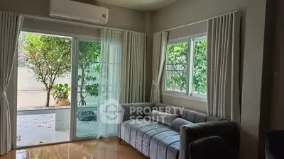 Cozy living room with plush sofa and garden view through large windows.