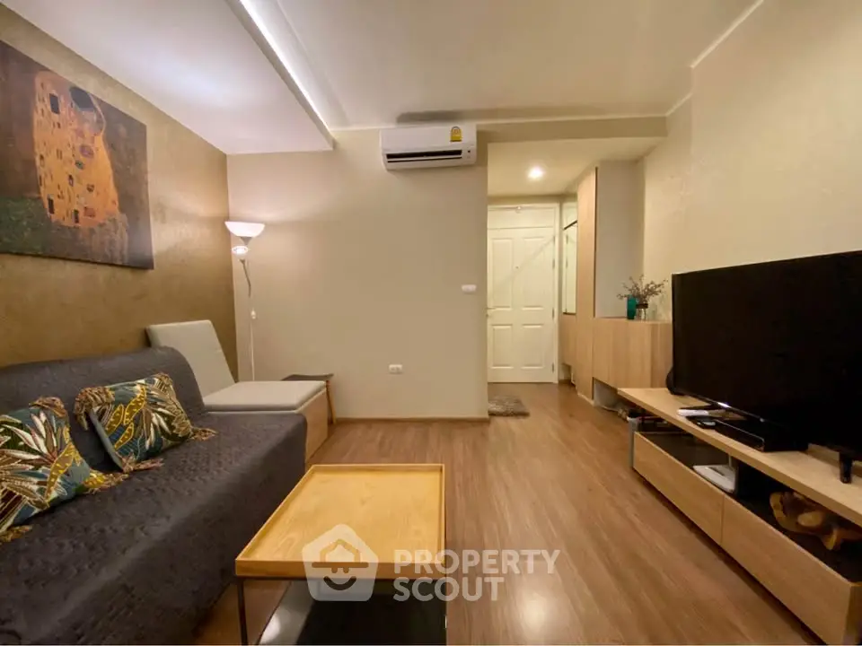 Modern living room with stylish decor and wooden flooring, featuring a cozy sofa and large flat-screen TV.