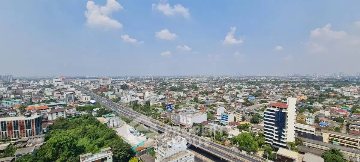 Panoramic cityscape view showcasing urban skyline and residential areas under a clear blue sky.