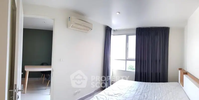 Bright bedroom with large window and air conditioning unit, adjacent to a study area.