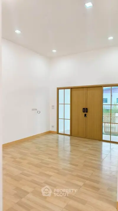 Spacious empty room with wooden sliding doors and bright lighting