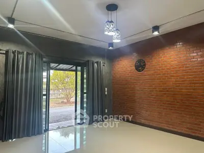 Modern living room with brick accent wall and stylish lighting, featuring large windows for natural light.