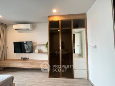 Modern bedroom with sleek wooden furniture and wall-mounted TV, featuring a stylish wardrobe and air conditioning.