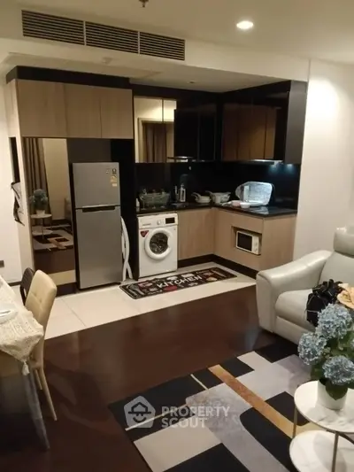 Modern kitchen with sleek appliances and cozy living area in open layout apartment.
