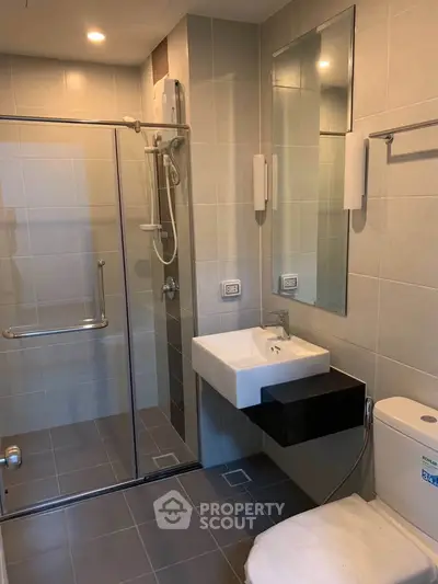 Modern bathroom with glass shower and sleek fixtures in contemporary apartment.