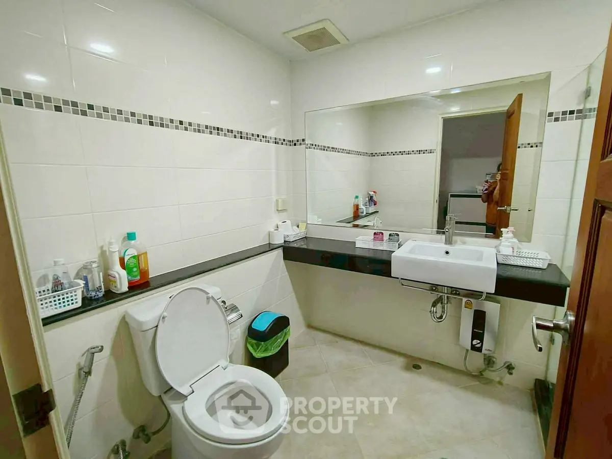 Modern bathroom with sleek fixtures and large mirror, ideal for contemporary living.