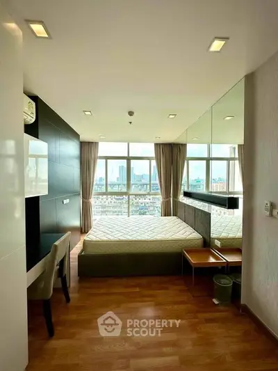 Spacious bedroom with city view, modern decor, and large windows for natural light.