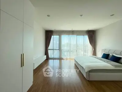 Spacious modern bedroom with large windows and elegant decor, offering abundant natural light and serene ambiance.