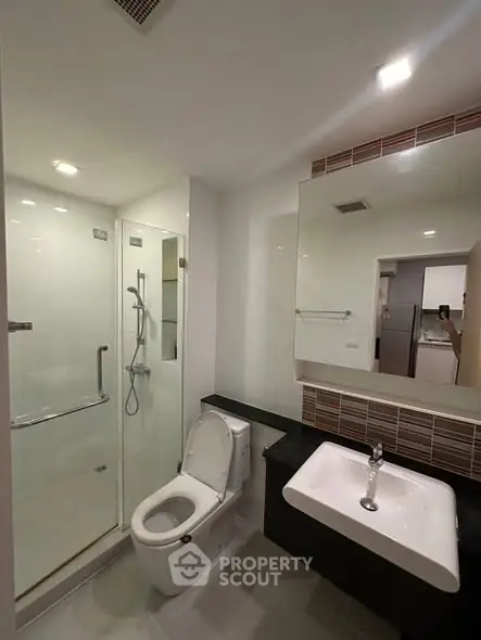 Modern bathroom with glass shower and sleek fixtures in a contemporary apartment.