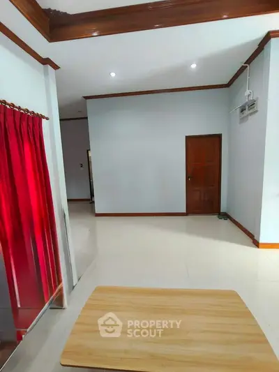 Spacious interior with elegant wooden accents and vibrant red curtains, perfect for modern living.