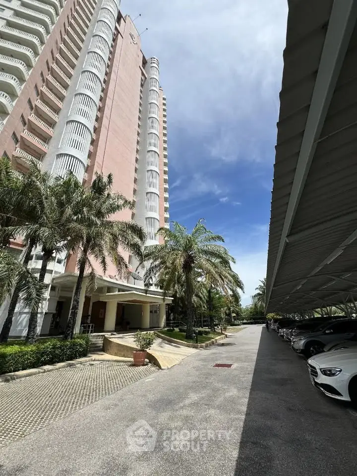 Stunning high-rise building with lush palm trees and covered parking area.