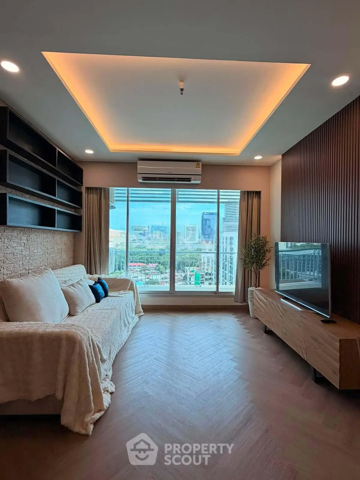 Modern living room with city view, featuring cozy sofa and sleek TV setup.