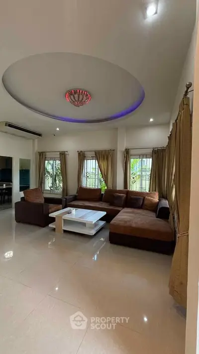 Spacious living room with modern ceiling design and large sectional sofa, perfect for family gatherings.